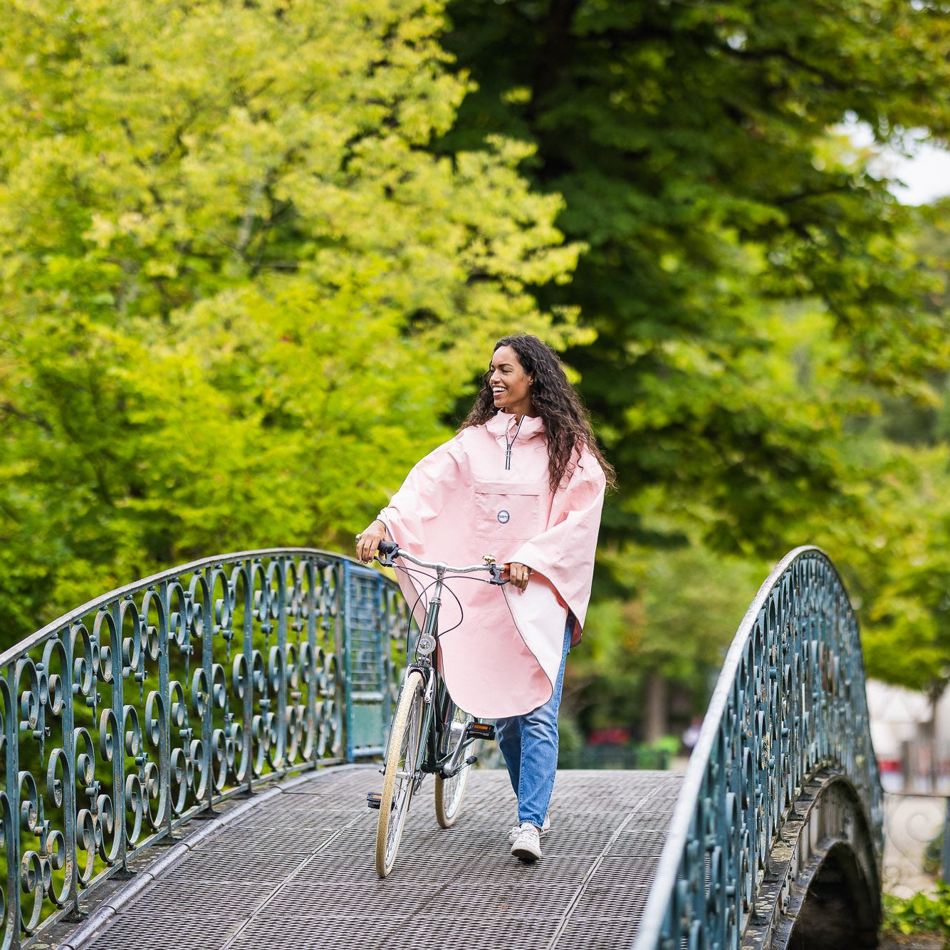 Utilisateur à vélo portant la cape Cap Dagde 100 % recyclée, protection imperméable adaptée aux trajets quotidiens.