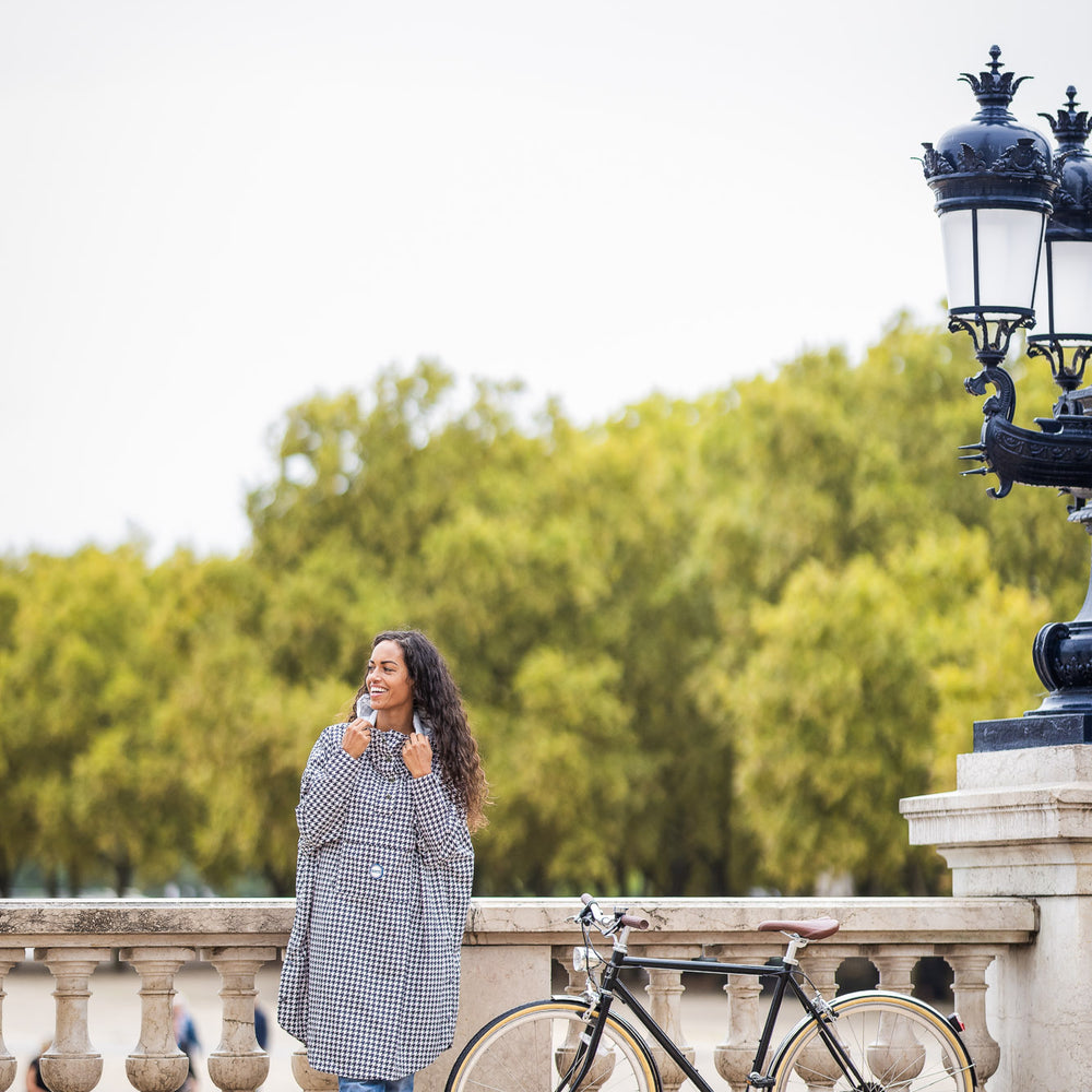 Utilisateur à vélo portant le poncho Paris recyclable, coupe imperméable.