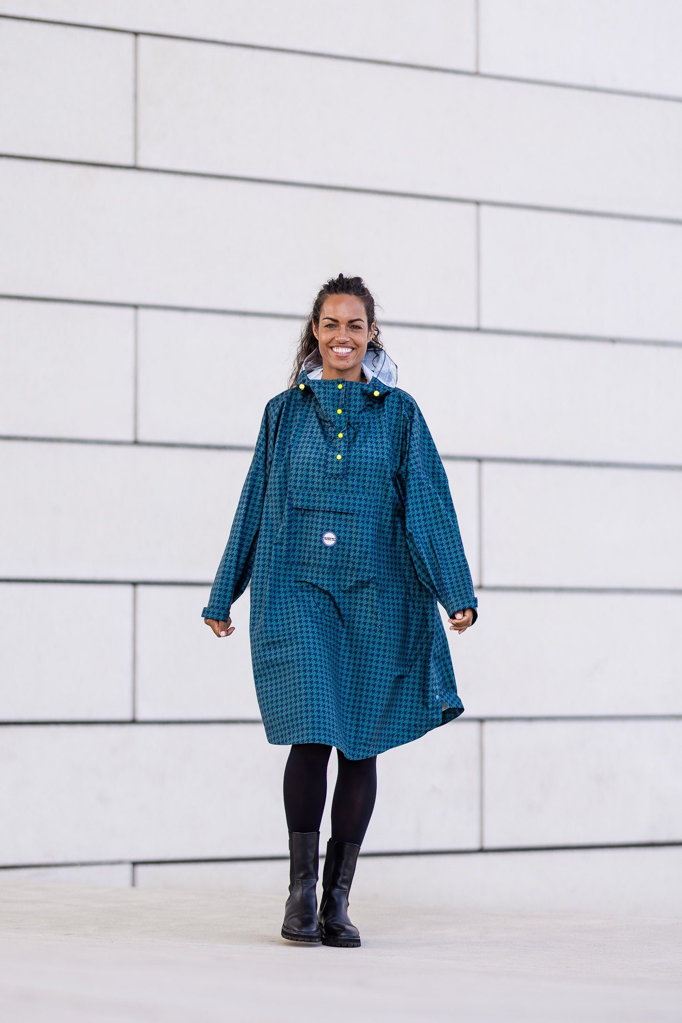 Poncho Anvers en pied de poule vert et bleu marine avec pochette de rangement intégrée et finition boutons jaune.