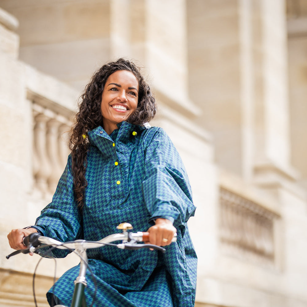 Utilisateur heureux portant le poncho Anvers en pied de poule vert et bleu marine, protection imperméable pour vélo ou balade sous la pluie.