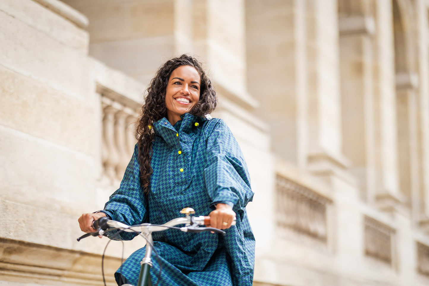 Utilisateur heureux portant le poncho Anvers en pied de poule vert et bleu marine, protection imperméable pour vélo ou balade sous la pluie.