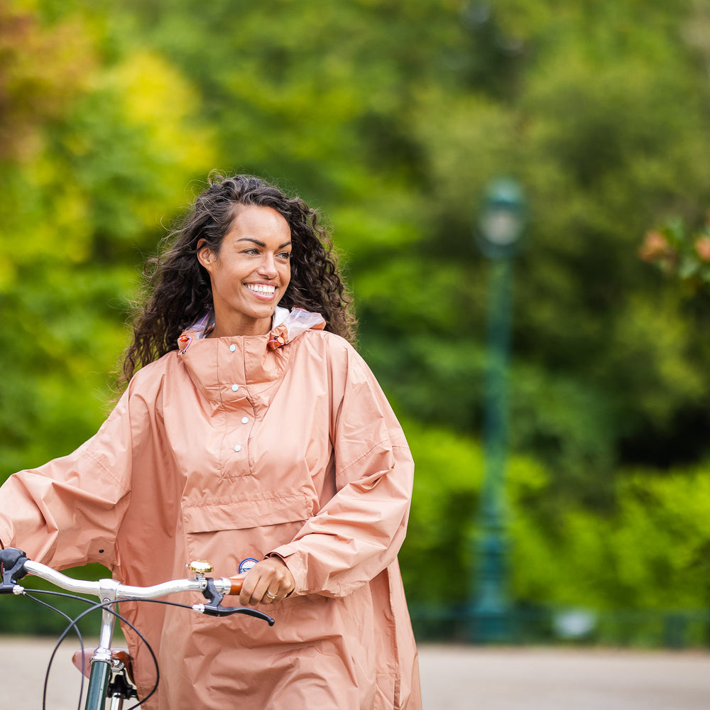 
                      
                        Utilisateur à vélo portant le poncho Dublin, coupe ample avec capuche, protection imperméable contre la pluie
                      
                    