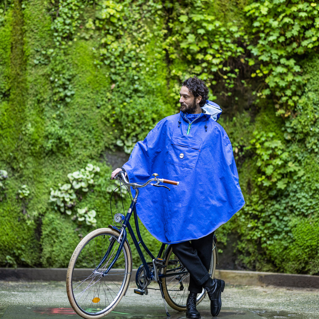 Utilisateur à vélo sous la pluie avec la cape Cap Cod, tissu imperméable 100 % recyclé.
