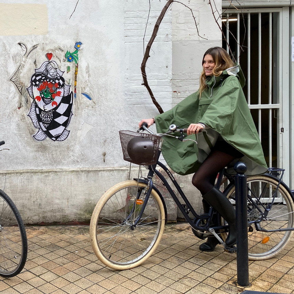 Personne à vélo sous la pluie portant la cape Cap Vert recyclée, protection imperméable.